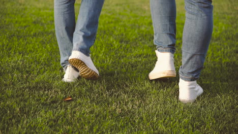 Close-Up-Of-Legs-Of-Unrecognizable-Couple-Walking-On-Grass-In-The-Park