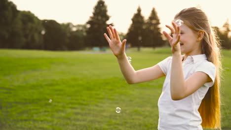Happy-Little-Girl-Catching-Soap-Bubbles-In-The-Park
