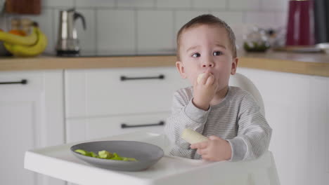 Lindo-Bebé-Comiendo-Plátano-Sentado-En-Una-Silla-Alta-En-La-Cocina-2