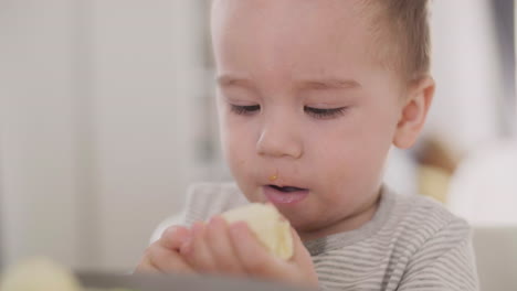 Close-Up-Of-An-Adorable-Baby-Boy-Eating-Banana-At-Home