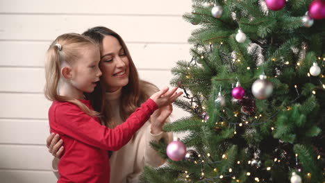 Mother-With-Her-Daughter-Hanging-Christmas-Ornaments-On-Christmas-Tree-1