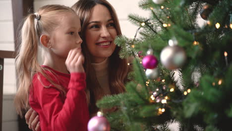 Mother-With-Her-Daughter-Hanging-Christmas-Ornaments-On-Christmas-Tree-3