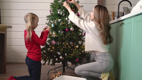 Mutter-Mit-Ihrer-Tochter-Nimmt-Weihnachtsschmuck-Aus-Einer-Kiste-Und-Hängt-Ihn-An-Den-Weihnachtsbaum-1