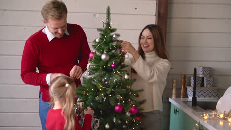 Glückliches-Paar-Und-Ihre-Tochter-Hängen-Weihnachtsdekoration-Am-Weihnachtsbaum-Zu-Hause