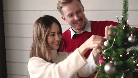 Glückliches-Paar,-Das-Zu-Hause-Weihnachtsdekoration-Am-Weihnachtsbaum-Hängt-3