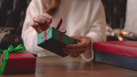 Close-Up-View-Of-Woman-Hands-Wrapping-A-Christmas-Present-With-A-Bow-On-A-Table-1