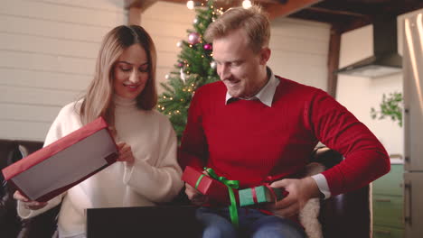 Frau-Und-Mann,-Die-Weihnachtsgeschenke-Einpacken,-Sitzen-Auf-Dem-Sofa-Neben-Einem-Weihnachtsbaum-Im-Wohnzimmer
