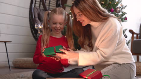 Mutter-Und-Tochter-Packen-Weihnachtsgeschenke-Ein-Und-Sitzen-Auf-Dem-Boden-Neben-Einem-Weihnachtsbaum-Im-Wohnzimmer