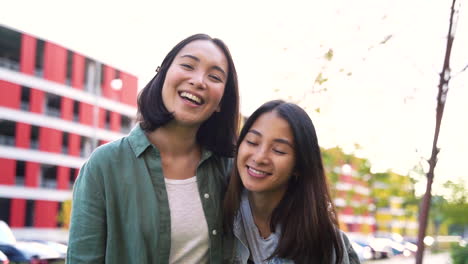 Two-Happy-Japanese-Female-Friends-Laughing-And-Making-V-Sign-While-Looking-At-Camera-In-The-Street