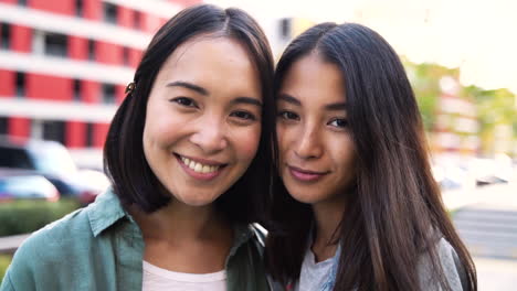 Outdoor-Portrait-Of-Two-Beautiful-Young-Japanese-Girls-Looking-And-Smiling-At-Camera-1