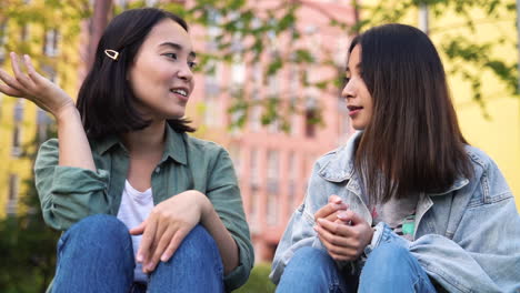 Dos-Chicas-Japonesas-Muy-Jóvenes-Sentadas-Y-Hablando-Juntas-Al-Aire-Libre