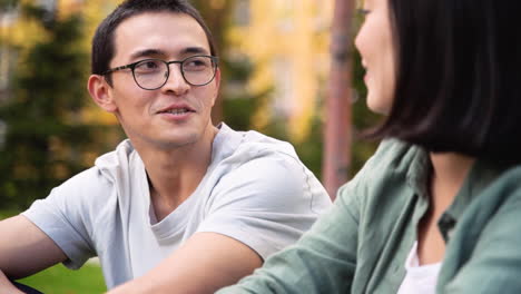 Young-Japanese-Man-Talking-To-His-Female-Friend-While-Sitting-Together-Outdoors-1