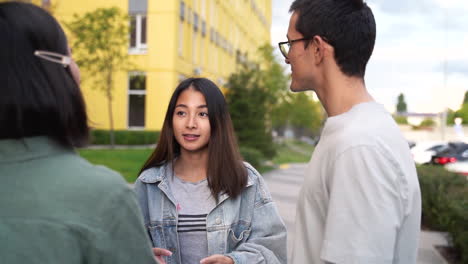 Group-Of-Three-Happy-Young-Japanese-Friends-Standing-Outdoors-And-Talking-To-Each-Other-1
