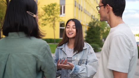 Group-Of-Three-Happy-Young-Japanese-Friends-Standing-Outdoors-And-Talking-To-Each-Other-2