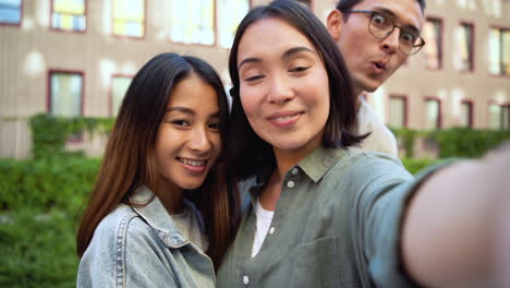 Group-Of-Three-Young-Japanese-Friends-Looking-At-Camera-And-Taking-Selfie-Photos-Together