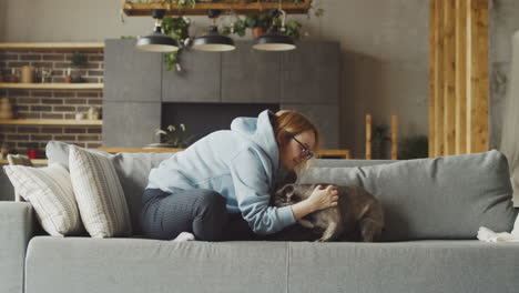 Red-Haired-Woman-Caresses-Her-Bulldog-Dog-While-They-Are-Sitting-On-The-Sofa-In-The-Living-Room-At-Home-1