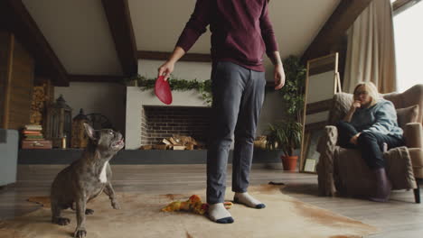 Mann-Steht-Beim-Spielen-Mit-Ihrem-Hund-Im-Wohnzimmer-Zu-Hause