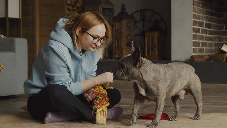 Red-Haired-Woman-Caresses-Her-Bulldog-Dog-While-They-Are-Sitting-On-The-Floor-In-The-Living-Room-At-Home