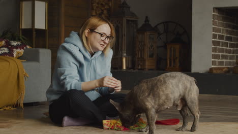 Red-Haired-Woman-Caresses-Her-Bulldog-Dog-While-Shi-Is-Sitting-On-The-Floor-In-The-Living-Room-At-Home