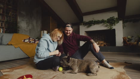 Couple-Playing-With-Her-Bulldog-Dog-With-A-Tennis-Ball-On-The-Floor-In-Living-Room-3