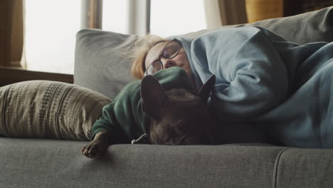 Red-Haired-Woman-Sleeping-With-Her-Bulldog-Dog-On-The-Couch-In-The-Living-Room-At-Home