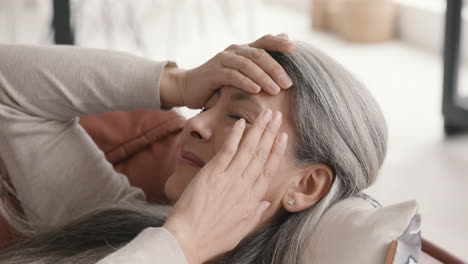 Kranke-Frau-Mittleren-Alters,-Die-Kopfschmerzen-Hat,-Während-Sie-Zu-Hause-Zugedeckt-Auf-Der-Couch-Liegt-1