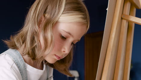Close-Up-View-Of-A-Girl's-Face-Concentrating-And-Painting-On-A-Lectern-In-Living-Room