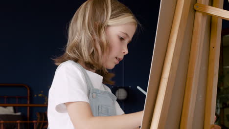 Close-Up-View-Of-A-Girl's-Face-Concentrating-And-Painting-On-A-Lectern-In-Living-Room-1