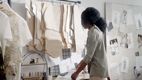 Young-Woman,-Clothing-Designer-Examining-Sketch-Clothes-And-Choosing-The-Best-For-New-Collection-In-Her-Studio