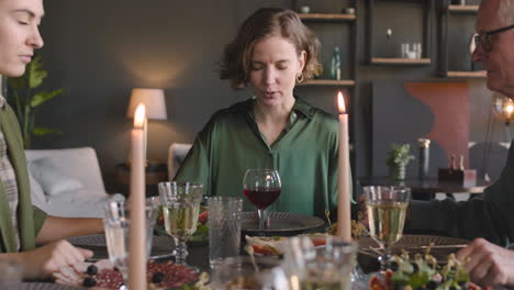 Adult-Woman-Holding-Her-Relatives-Hands-And-Praying-Before-Meal-While-Sitting-At-Dinner-Table-At-Home
