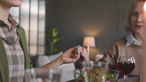 Close-Up-Of-Mother-And-Daughter-Holding-Hands-And-Praying-Before-Meal-At-Home