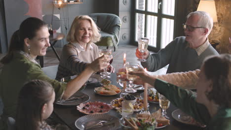 Happy-Family-Toasting-Each-Other-While-Having-Dinner-Together-At-Home