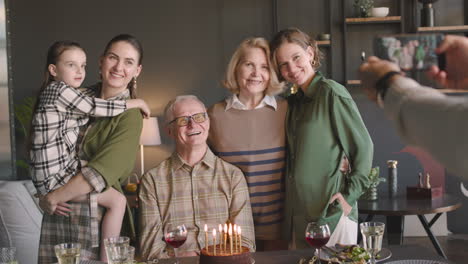 Anciano-Y-Su-Familia-Posando-Y-Sonriendo-A-La-Cámara-Del-Teléfono-Móvil-Durante-Su-Fiesta-De-Cumpleaños-En-Casa