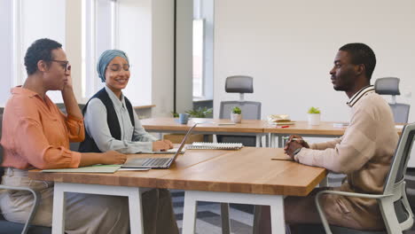 An-Woman-And-A-Muslim-Woman-Co-Workers-Interview-A-Young-Man-Sitting-At-A-Table-In-The-Office-15