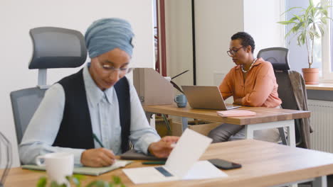 Close-Up-View-Of-Muslim-Businesswoman-Taking-Notes-And-Businesswoman-In-The-Background-1