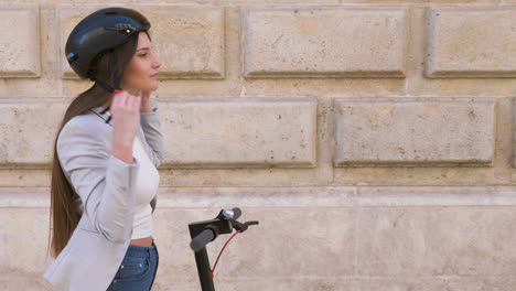Smiling-Young-Woman-Putting-On-Helmet-And-Riding-Electric-Scooter-In-The-City