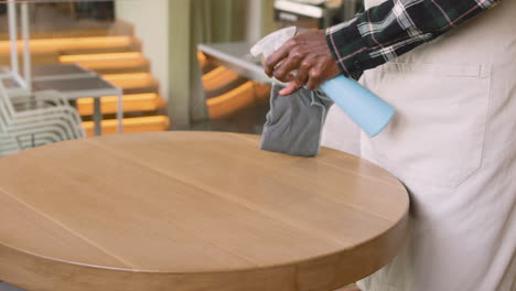 Waiter-Cleaning-Coffe-Shop-Table-With-Disinfectant-Spray-And-Rag