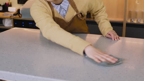 Waitress-Cleaning-Bar-Counter-With-Rag-While-Working-In-Coffee-Shop-2