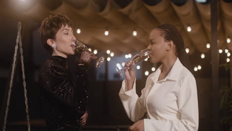 Two-Elegant-Multiethnic-Women-Toasting-And-Drinking-Champagne-At-New-Year's-Eve-Party-1