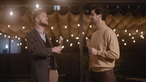 Two-Elegant-Men-Talking-To-Each-Other-And-Drinking-Champagne-At-New-Year's-Eve-Party