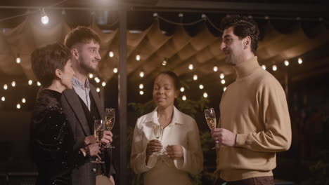 Gruppe-Von-Vier-Multiethnischen-Freunden,-Die-Champagnergläser-Halten-Und-Sich-Auf-Der-Silvesterparty-Unterhalten