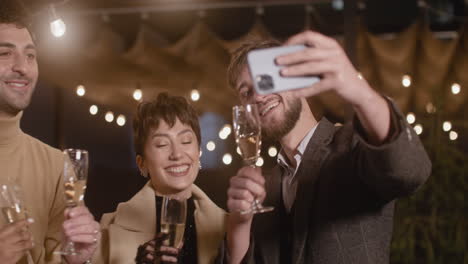 Portrait-Of-Group-Of-Four-Happy-Multiethnic-Friends-Taking-A-Selfie-Video-And-Toasting-With-Champagne-Glasses-At-New-Year's-Eve-Party-1