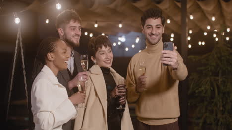 Portrait-Of-Group-Of-Four-Happy-Multiethnic-Friends-Taking-A-Selfie-Video-And-Toasting-With-Champagne-Glasses-At-New-Year's-Eve-Party-2
