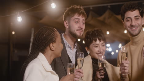 Portrait-Of-Group-Of-Four-Happy-Multiethnic-Friends-Holding-Champagne-Glasses-And-Taking-A-Selfie-Video-At-New-Year's-Eve-Party