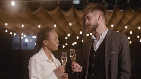 Man-And-Woman-Holding-Champagne-Glasses-And-Talking-To-Each-Other-At-New-Year's-Eve-Party-1