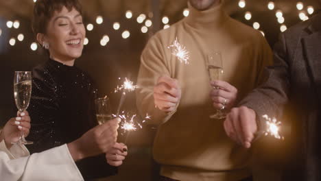 Group-Of-Four-Multiethnic-Friends-With-Champagne-Glasses-Having-Fun-With-Sparklers-At-New-Year's-Eve-Party
