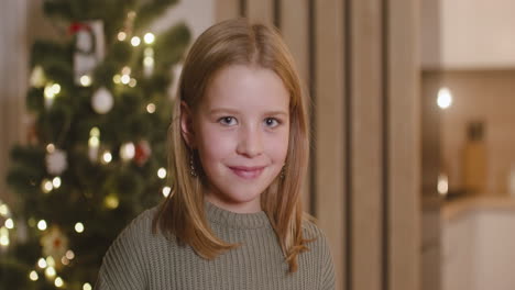 Vorderansicht-Eines-Blonden-Mädchens,-Das-In-Einem-Mit-Einem-Weihnachtsbaum-Geschmückten-Raum-In-Die-Kamera-Lächelt-1