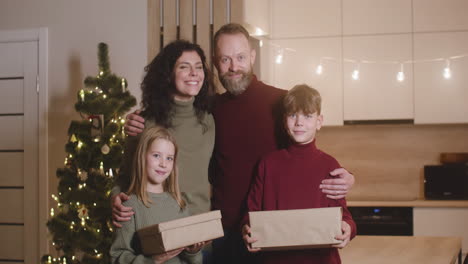 Vorderansicht-Einer-Familie,-Die-In-Die-Kamera-Lächelt,-In-Einem-Raum,-Der-Mit-Einem-Weihnachtsbaum-Geschmückt-Ist