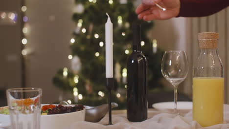 Camera-Focuses-On-Man's-Hands-Lighting-A-Candle-That-Decorates-The-Christmas-Table-Setting
