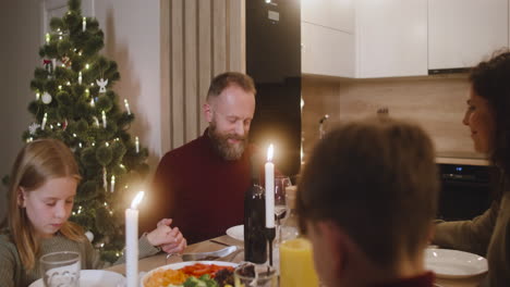Couple-And-Their-Children-Pray-And-Bless-The-Table-Before-Christmas-Family-Dinner-2